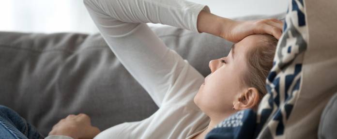 Frau liegt müde auf der Couch