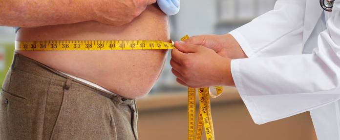 Arzt misst Bauchumfang eines fettleibigen Mannes
