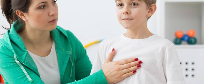 Physiotherapeutin legt Hand auf den Brustkorb eines Kindes