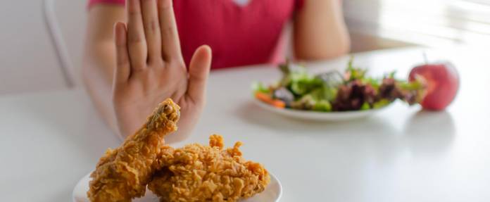 Frau schiebt frittiertes Essen weg mit der Hand