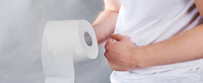 Mann mit Bauchschmerzen und Toilettenpapier in der Hand