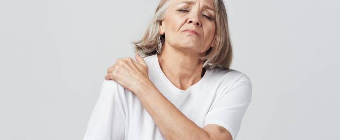 Ältere Frau fasst sich an die schmerzende Schulter