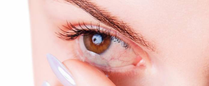Frau mit entzündeten Augen entfernt Kontaktlinse
