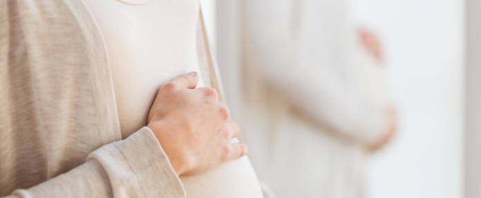 Schwangere Frau hält Ihre Hände um den Bauch
