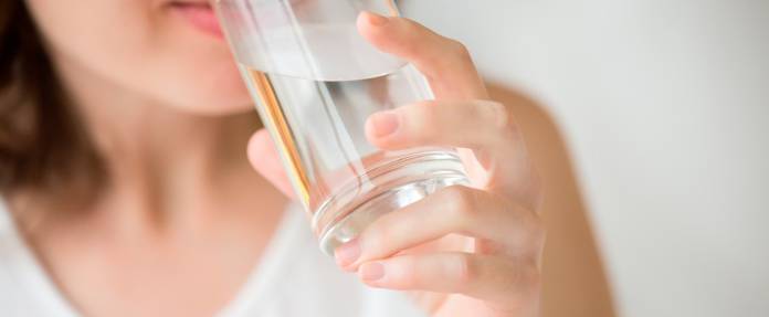 Frau trinkt Wasser aus Glas