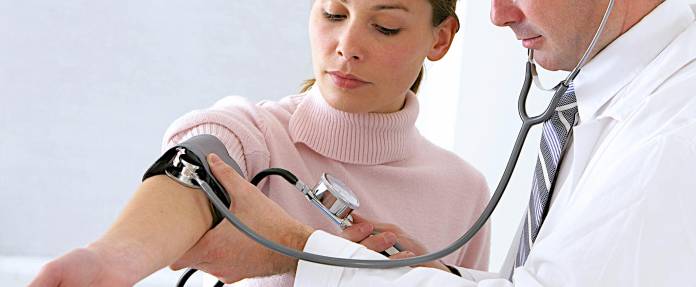 Frau beim Arzt bei Blutdruckmessung