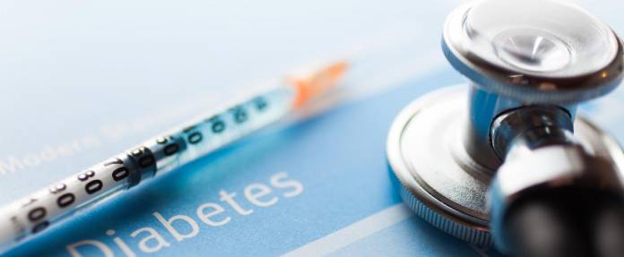 Diabetes Schriftzug mit Stethoskop und Insulinspritze im Bild liegend