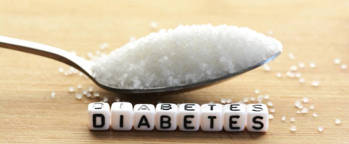 Ein Löffel Zucker und aus Buchstaben das Wort Diabetes gelegt