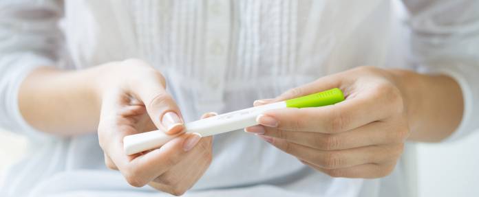 Frau mit Schwangerschaftstest in der Hand