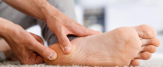 Mann massiert schmerzende Ferse