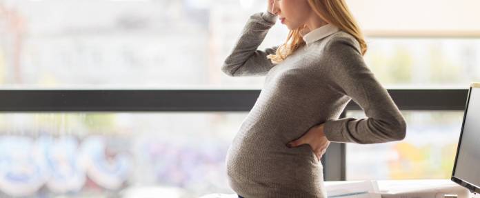 Schwangere Frau gestresst am Arbeitsplatz