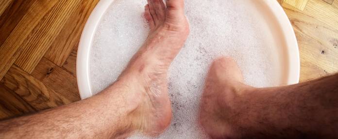 Mann hält Füße in eine Schüssel mit Seifenwasser