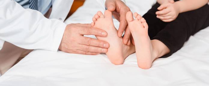 Arzt untersucht Füße eines Kindes