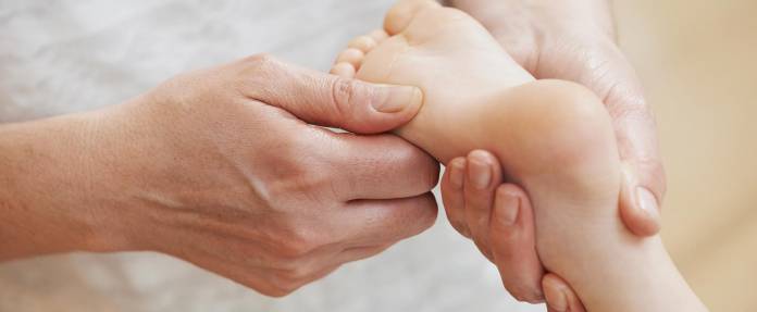 Mann begutachtet Kinderfuß mit den Händen