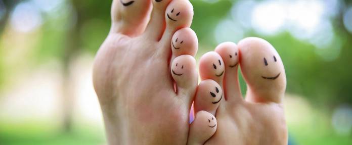 Füße mit aufgemalten lachenden Gesichtern auf den Zehenrückseiten