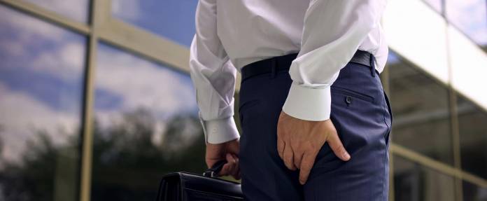 Mann mit Schmerzen am Hintern beim Gehen