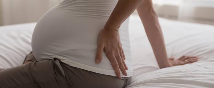 Schwangere Frau mit Schmerzen am Rücken und Gesäß