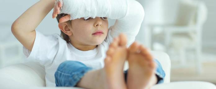 Junge mit Gipsarm auf dem Sofa