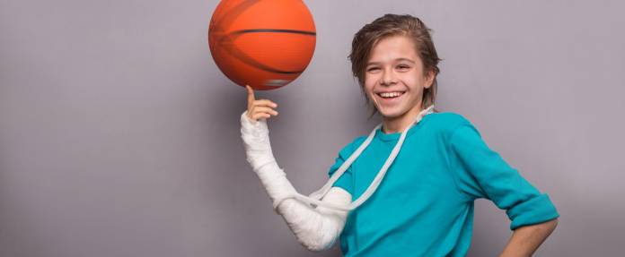 Junge mit Gipsarm und Basketball 