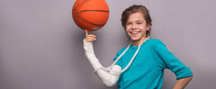 Junge mit Gipsarm und Basketball 