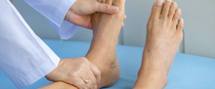 Arzt tastet Füße einer Patientin ab
