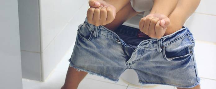 Frau sitzt auf der Toilette und presst stark