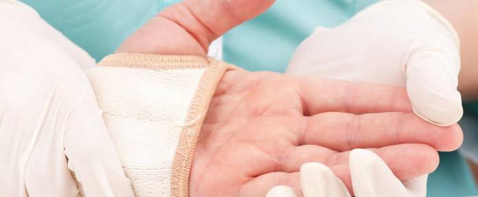 Arzt begutachtet Hand eines Patienten mit Manschette