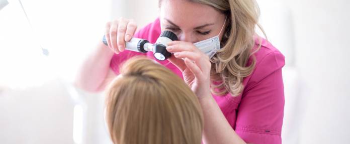 Dermatologin untersucht Kopfhaut einer Patientin