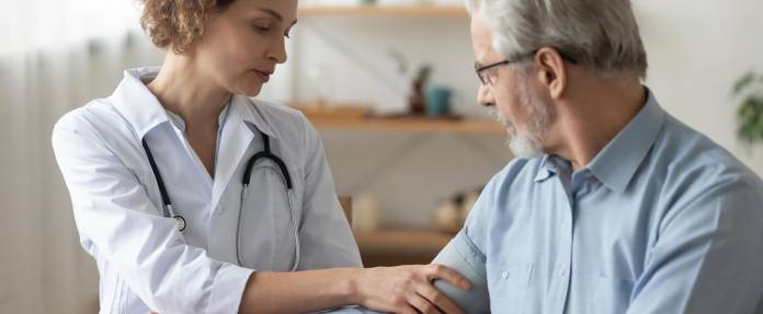 Ärztin misst Blutdruck bei älterem Patienten