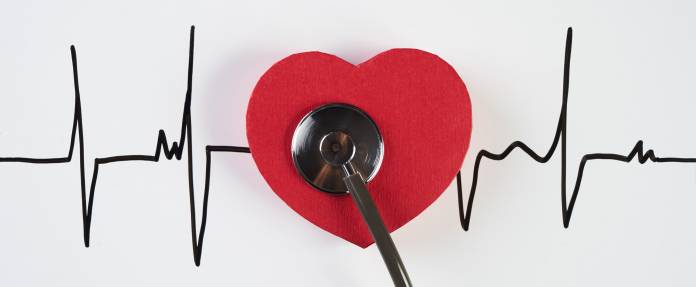 Stethoskop mit rotem Herz auf Kardiogramm liegend