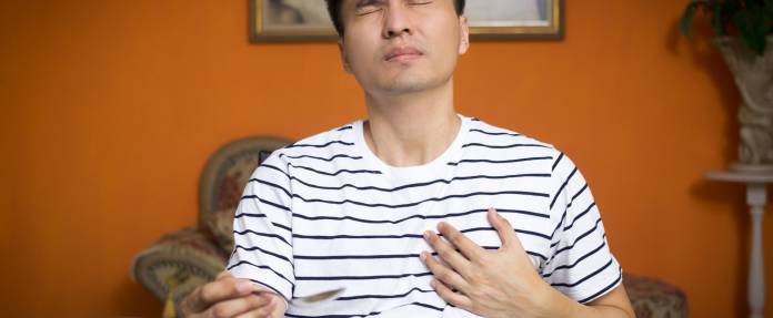 Asiatischer Mann mit Herzproblemen während dem Essen