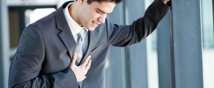 Junger Mann mit Herzschmerzen wegen Stress im Büro