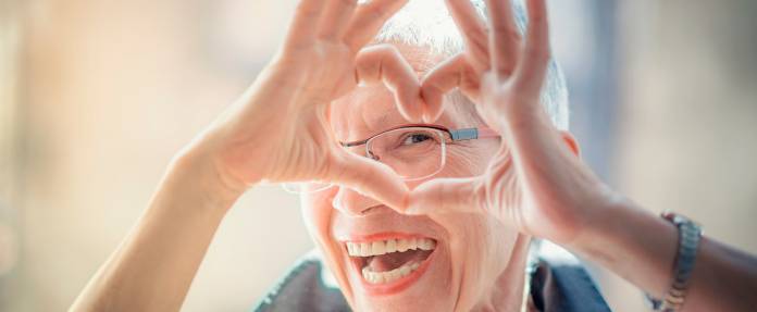 Seniorin formt Herz mit ihren Fingern