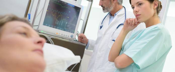 Arzt und Krankenpflegerin überprüfen den Herzschlag einer Patientin