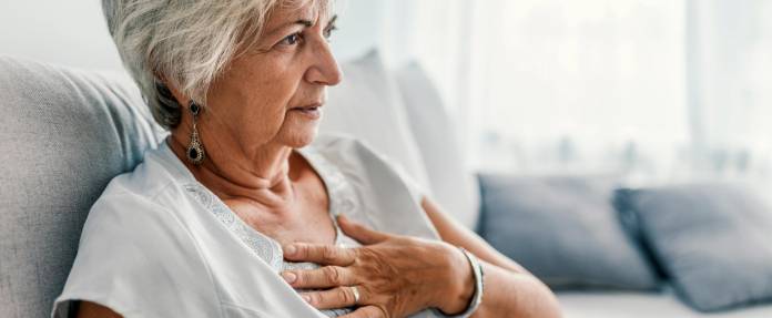 Ältere Frau mit Atembeschwerden sitzend auf dem Sofa