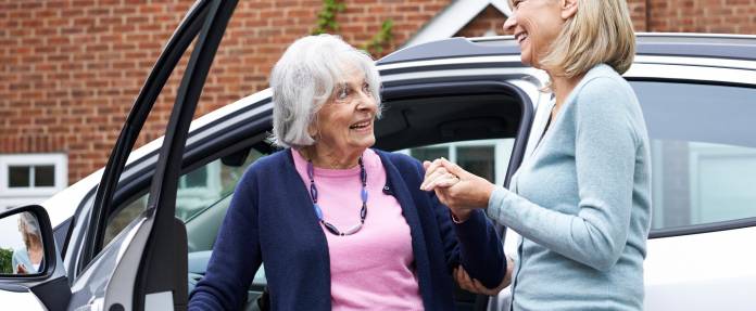 Ältere Frau wird beim Aussteigen aus dem Auto geholfen