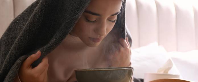 Frau beim Inhalieren unter einem Handtuch