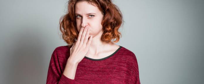 Frau mit Brechreiz hält sich Hand vor den Mund