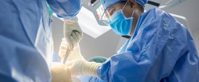Chirurg bei OP zur Implantation eines künstlichen Kniegelenks