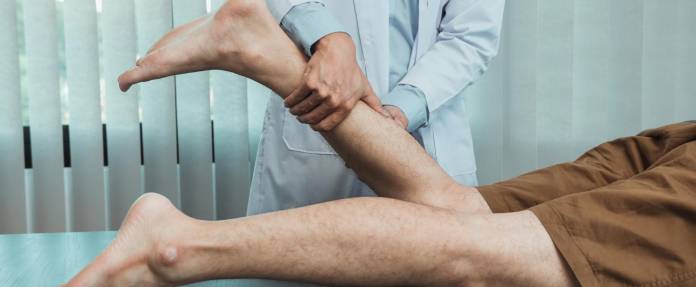 Arzt untersucht Wade eines Mannes