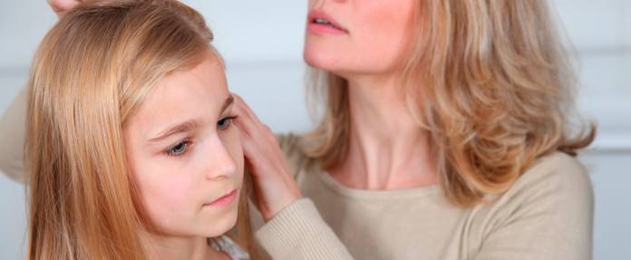 Mutter schaut sich die Haare und die Kopfhaut ihrer Tochter an