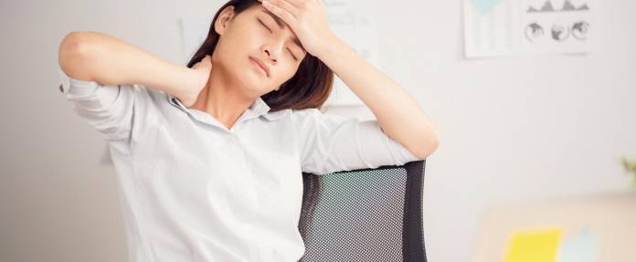 Frau im Büro mit Kopf- und Nackenschmerzen