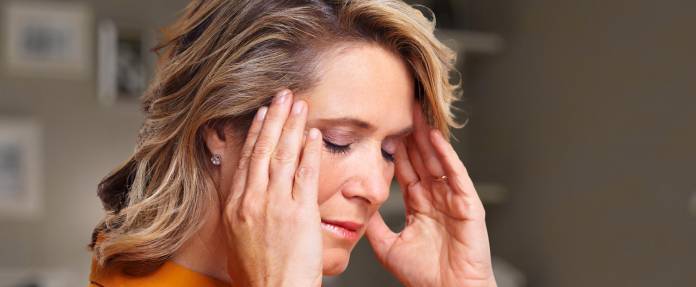 Frau fasst sich an die Schläfen wegen Kopfschmerzen