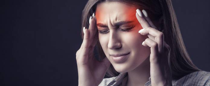 Junge Frau mit Kopfschmerzen fäßt sich an die Schläfen