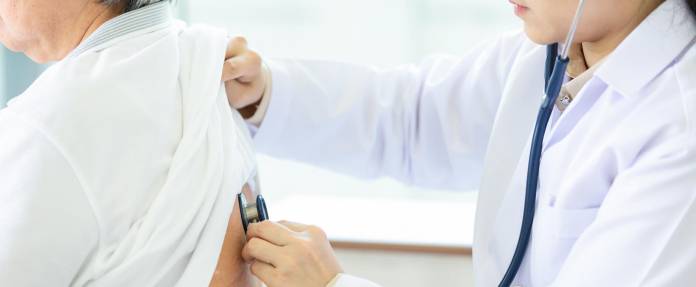 Arzt hört die Lunge einer älteren Frau mit dem Stethoskop ab