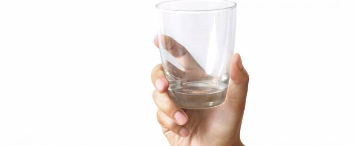 Leeres Wasserglas in der Hand