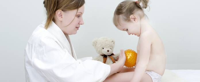 Kind bekommt Massage am Bauch von medizinischer Fachkraft