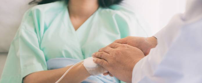 Frau im Krankenhaus mit Arzt, der ihr die Hand hält