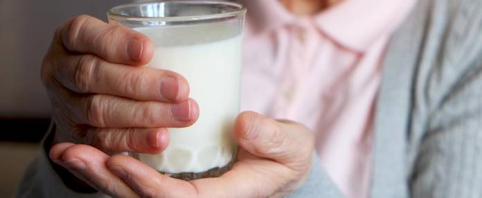 Seniorin hält ein Glas Milch in den Händen