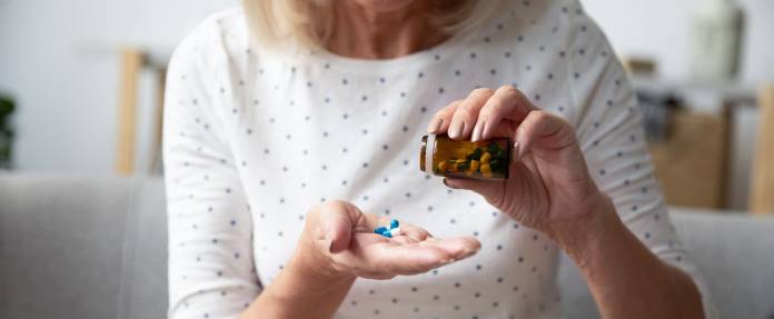 Frau kippt sich Tabletten auf die Hand